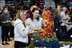 Two women employees select fruit from a fruit tower