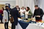 A group of staff select sandwiches from a table with a white table cloth