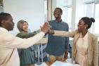 Four university students give a group high-five.