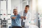 Older gentleman stretching alongside a rehabilitation expert. 