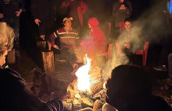 Participants of the Lake Shift 2024 pose for a photo around a roaring campfire.