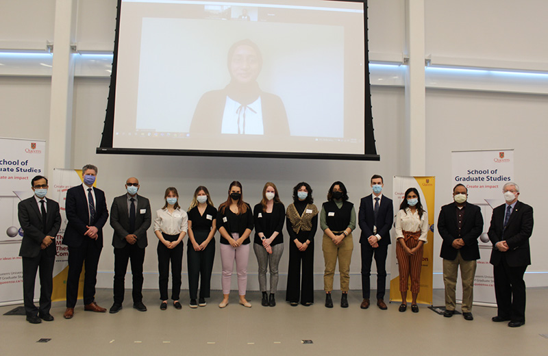 A group of people standing underneath a large projector screne.