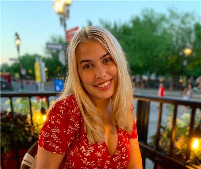 An image of Emily Viau smiling in a red shirt with an evening sky in the background