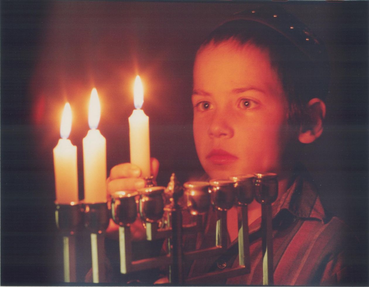A photo of a young child lighting a menorah