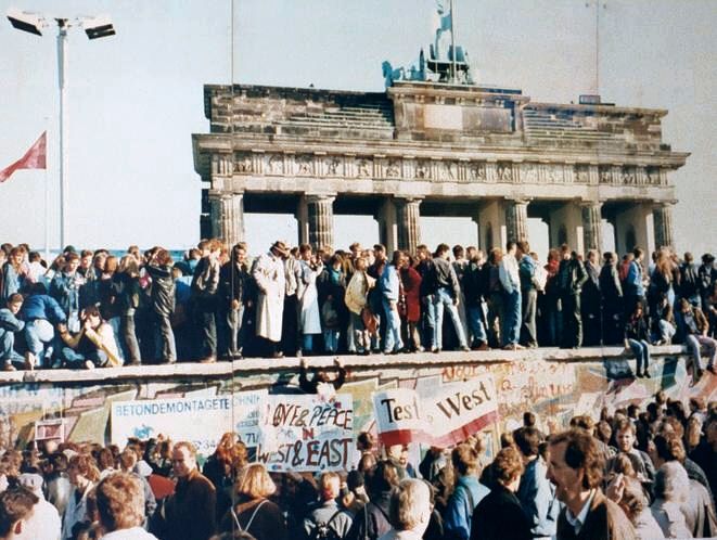 An image of a crowd standing on the Brandenburg Gate in Germany in 1989