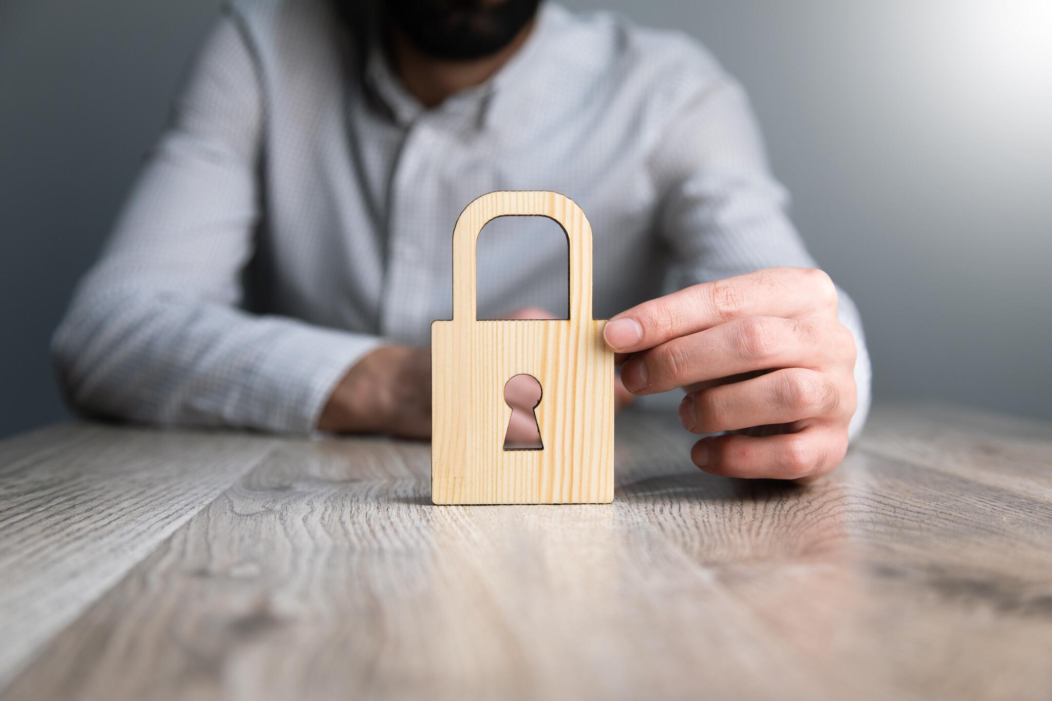 A man holds a wooden cut-out of a padlock.