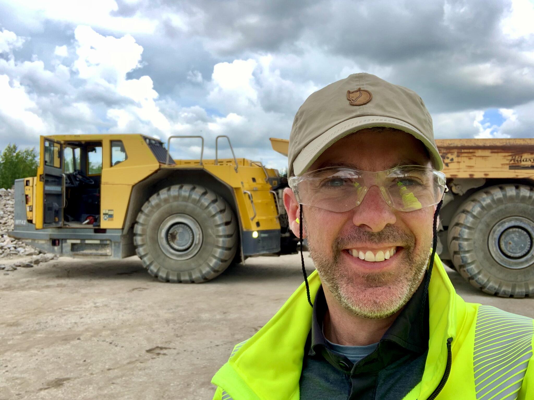 Josh in the field with a big mining truck.