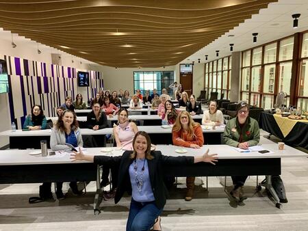 Kerry Ramsay in front of workshop attendees sitting at rows of desks