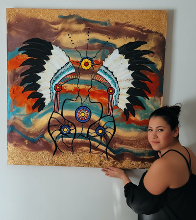 Jaylene Cardinal in front of one of her artwork pieces