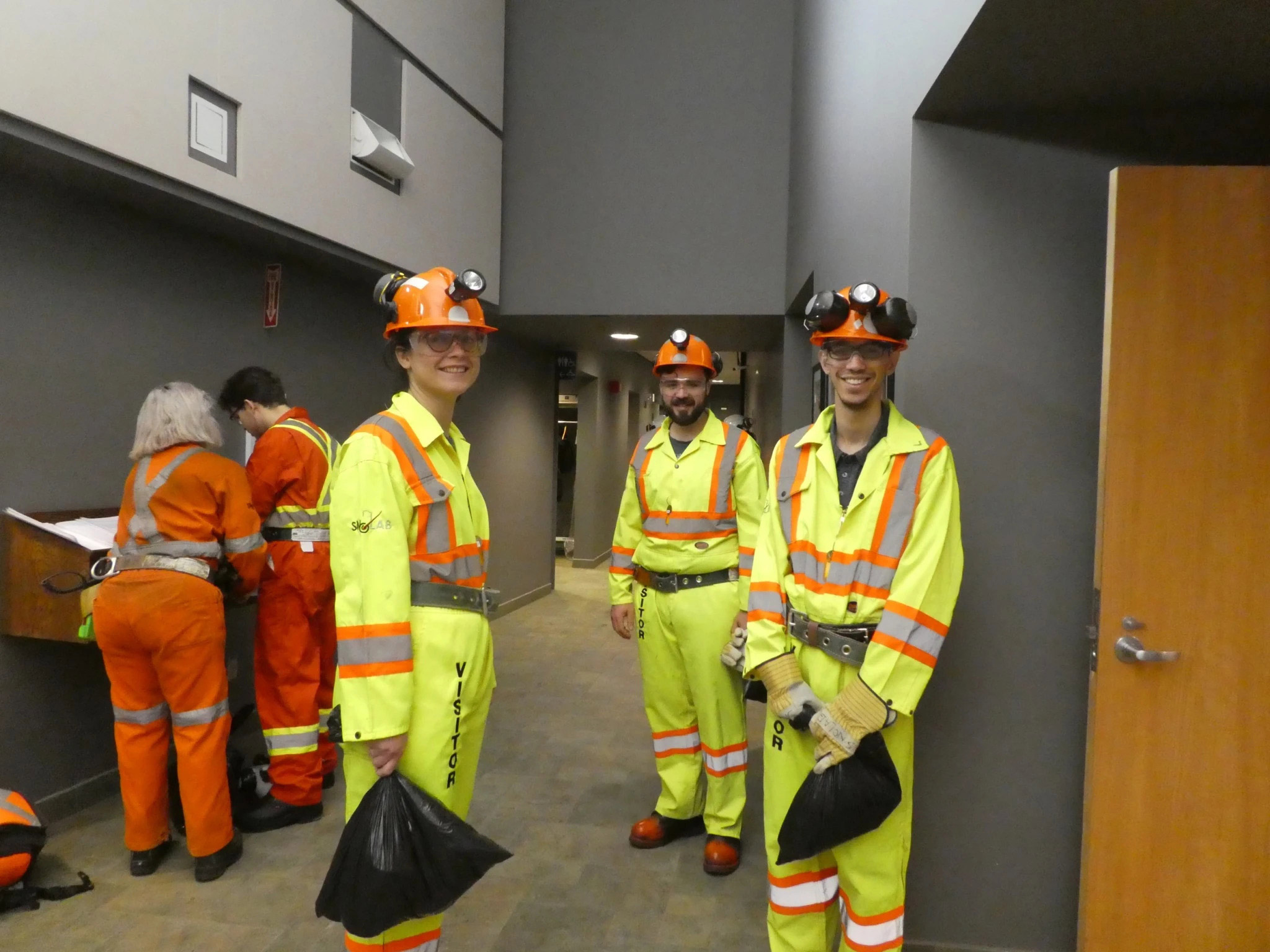 Holding their lunches in black bags and awaiting their descent into the mine.