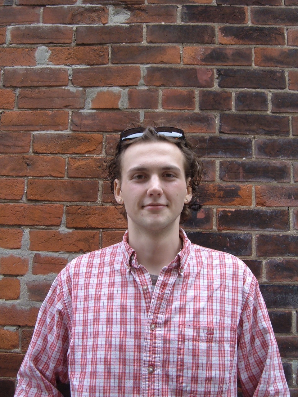 Young man standing in front of a brick wall