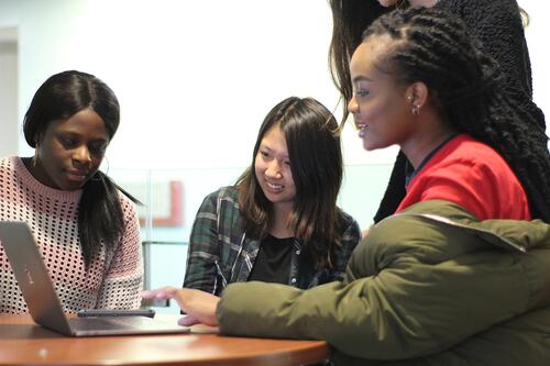 3 students sitting looking at a laptop