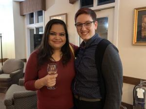 Two people smiling, one holding a drink