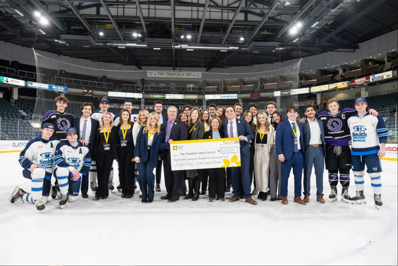 Hockey teams poses for a photo on the ice rink.