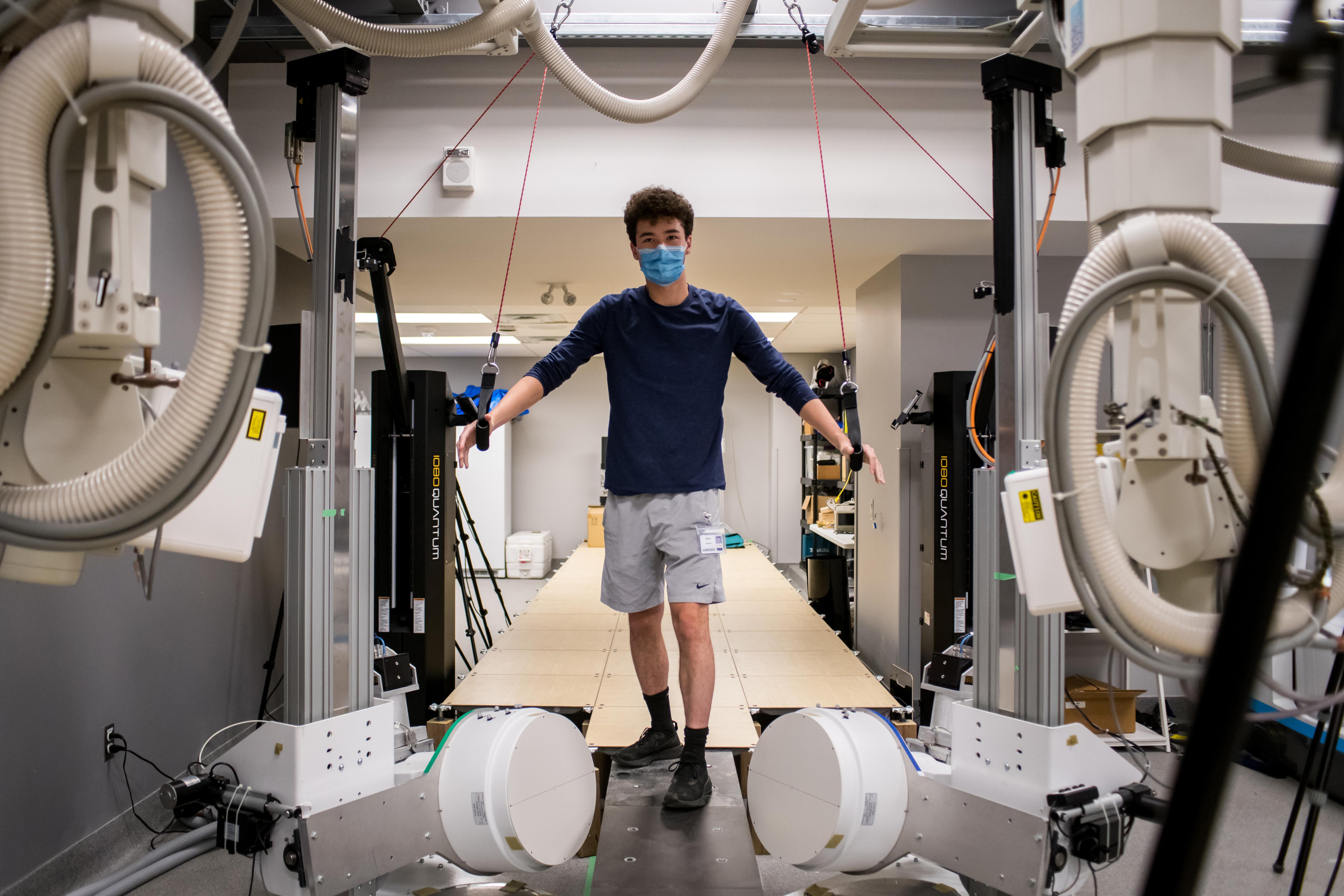 Student in human mobility lab using exercise equipment within large machine