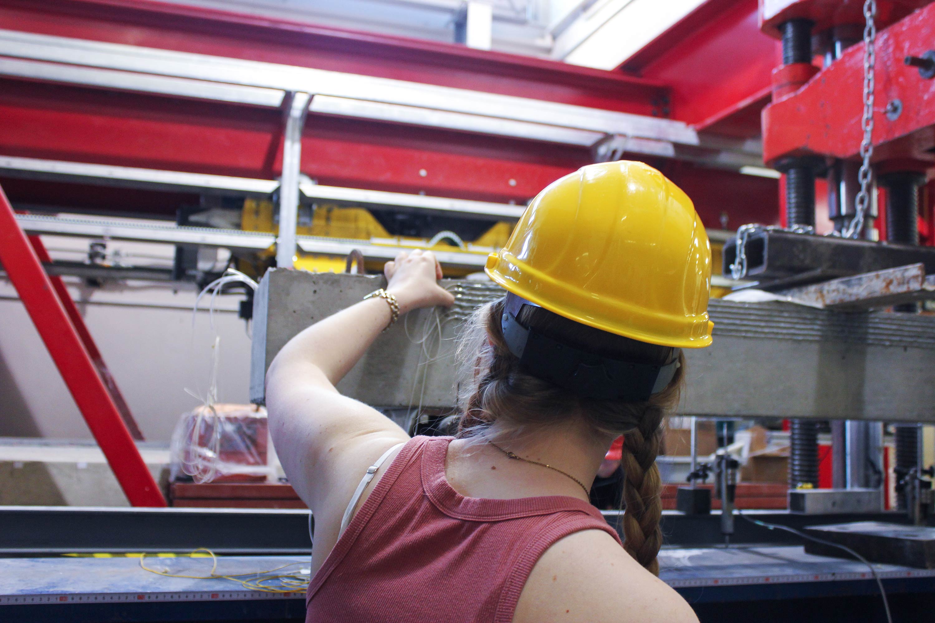 Student working in Civil Engineering lab, wearing hardhat and inspecting concrete