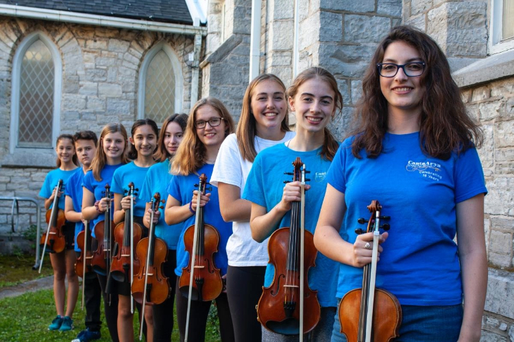 [A group of musicians from the Canta Arya School for Strings standing in front of St. James Anglican Church. ]