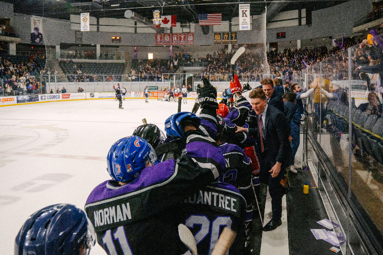 [A hockey team celebrates on an ice rink.]